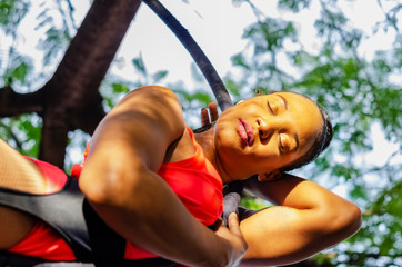 young woman practicing lyra, aerial hoop or aerial ring, outdoors, suspended and spinning doing stunts