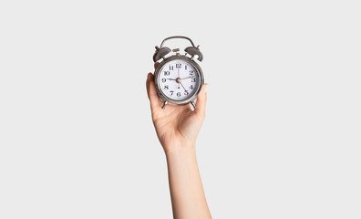 Time optimization concept. Female hand holding alarm clock on light background, close up