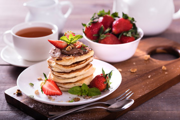 Pancakes  with chocolate sauce and fresh  strawberries on brawn wooden background. Delicious sweet dessert.