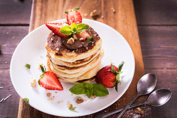 Pancakes  with chocolate sauce and fresh  strawberries on brawn wooden background. Delicious sweet dessert.
