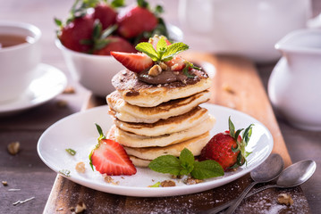 Pancakes  with chocolate sauce and fresh  strawberries on brawn wooden background. Delicious sweet dessert.