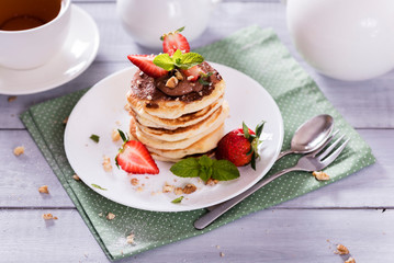 Pancakes  with chocolate sauce and fresh  strawberries on white wooden background. Delicious sweet dessert.