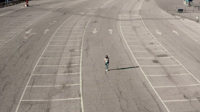 Woman standing alone in empty parking lot, COVID-19 coronavirus lockdown, aerial