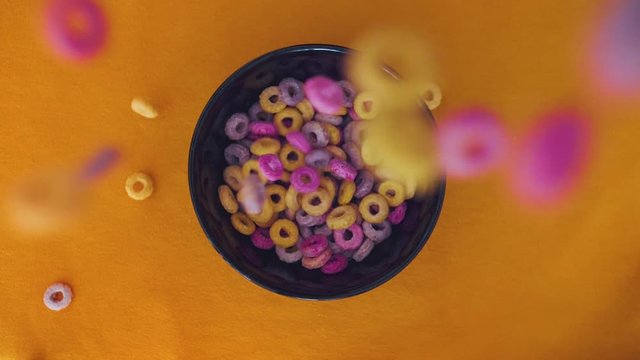 Colorful Cereals falling in  a bowl in slomotion topview.