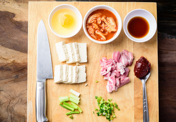 Kimchi soup cooking with ingredients and recipe on wooden board, Korean food (Kimchi Jjigae), Top view