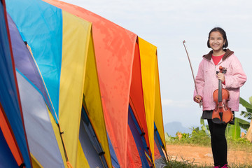 Portrait of an Asian girl and her violin in the morning during a holiday mountain camping