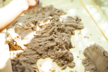 Child's hand playing with kinetic sand in preschool. The development of fine motor concept. Creativity Game concept.