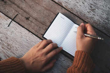 Copy space of woman hand writing down in white notebook with sun light background.