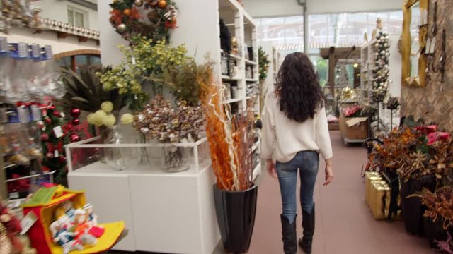 WS TS Young woman examining Christmas decorations on display shelves in store