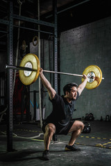 Fototapeta na wymiar asian strong athletic man having workout and bodybuilding with barbells weight lift over head squat style in gym and fitness club in dark two tone