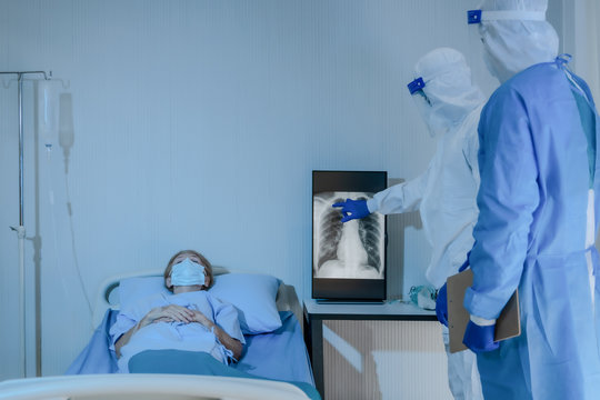 caucasian senior coronavirus covid-19 infected patient in quarantine room with doctor and medical team examining and doing sickness treatment - Powered by Adobe