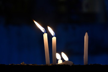 White candles are stuck in the dark, along with candles that are extinguished due to wind blowing and something falling to the ground. Concept of comparison with humans that uses light to guide life.
