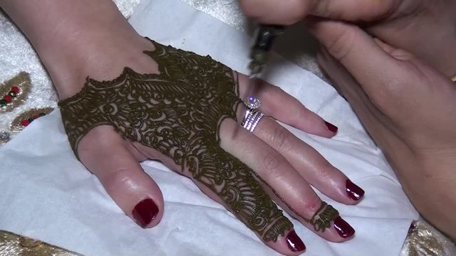 Applying a henna tattoo with a needle on a woman's hand. Closeup shot. Morocco.
