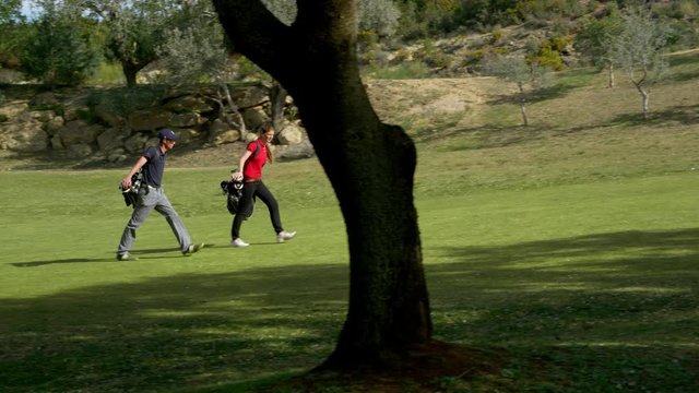 WS&nbsp;DS&nbsp;TS Two young golfers on fairway carrying golf bags along course