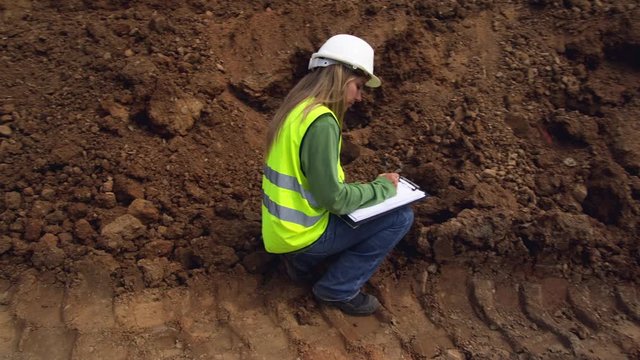 WS MS Female engineer taking soil samples and taking notes