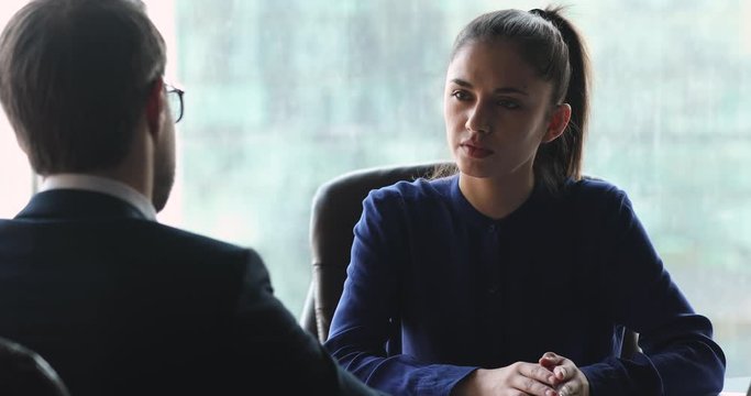 Head shot young successful confident smart businesswoman holding working meeting with male partner client in office. Focused female leader boss listening to employee colleague financial advisor.