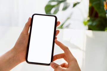 Hand holding smartphone mockup of blank screen on the table. Take your screen to put on advertising.