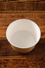 Big brown paper plate isolated on wooden background. Eco-friendly disposable food packaging. Preserving nature and recycling concept.