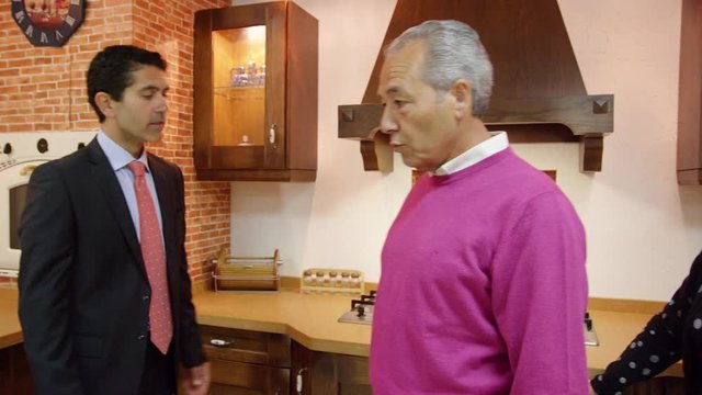 MS DS TS Salesman and mature couple in kitchen furniture showroom