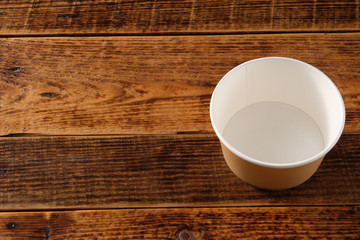 Big brown paper plate isolated on wooden background. Eco-friendly disposable food packaging. Preserving nature and recycling concept.