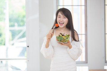 Beautiful Asian women, beautiful smiles, good health, beautiful teeth, eating salad vegetable when working at home.