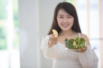 Beautiful Asian women, beautiful smiles, good health, beautiful teeth, eating salad vegetable when working at home.