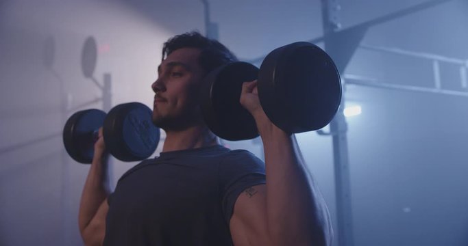 Male body builder working out in dark gym