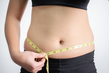 Young women measure belly fat with a fat tape. Isolated background.
