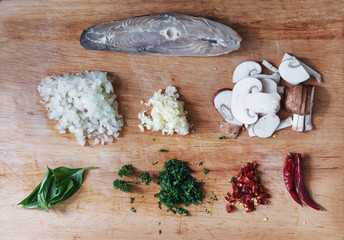 Raw food ingredients Garlic, Chili, Basil, Mushroom, Onion, Parsley and Salted Fish on wooden chopping board