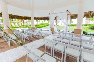 Colorful wedding arch gazebo pavilion made of bamboo and textile with fresh flowers decoration at sandy beach on sunny day for destination wedding ceremony in Dominican republic  