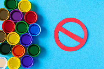 Plastic pollution. Plastic caps with stop sign on a blue background, minimalism. Recycling plastic, reusable packing, sorting garbage concept. Zero waste, ecology. Copyspase,