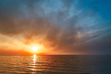Sea sunset. Smoke wildfires sweeping across the sky.