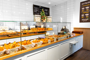 Baked baguettes and pies on showcase in bakery shop. Inscriptions in russian with the name baking