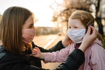 Coronavirus the end concept. No more covid-19. Little girl, mother wear masks walk on street. Mom removes mask happy child. Family with kid outdoors. celebrating success. Pandemic is over, has ended.