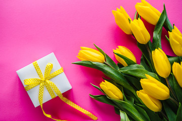 Bouquet of yellow tulips with gift box on pink background. Space for message. Flowers concept. Spring. Holiday greeting card for Valentine's, Women's, Mother's Day, Easter. Birthday. Top view.