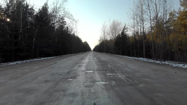 View from the windscreen of a car driving on a gravel road with poor surface quality with many holes and puddles. The concept of remote hard-to-reach areas. Outside the window is Sunny weather