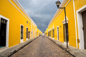 Beautiful perspective yellow street of the famous city of Izamal in Mexico. A snow-white carriage...
