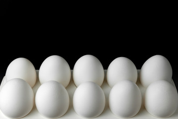 Eggs.Tray with white fresh chicken eggs on a black background close-up. Copy space.