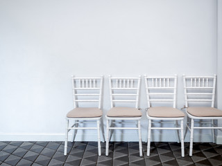 Row of white vintage wooden chairs with pads.