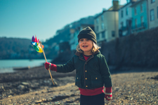 Preschooler boy with toy windmill on beach in town