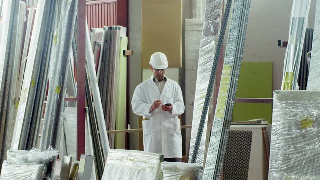 WS TS Man dressed in lab coat walking through furniture factory storage area