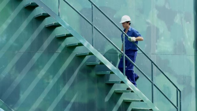 WS TS Worker ascending stairs on storage tank