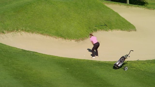 WS Mature female golfer hitting ball out of sand trap