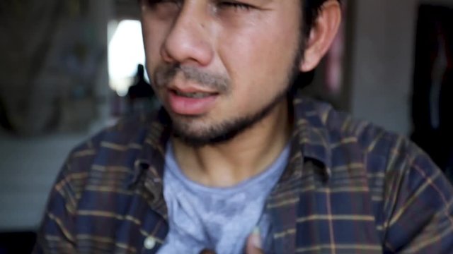 young asian man in casual t-shirt sweating from hot weather