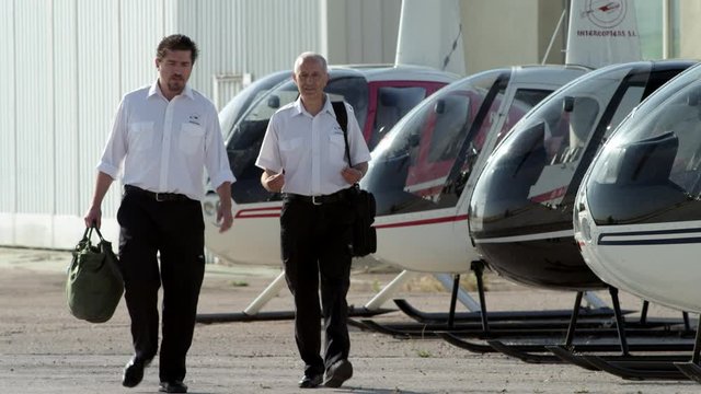 WS MS TS Two pilots walking towards camera along helicopter flight line