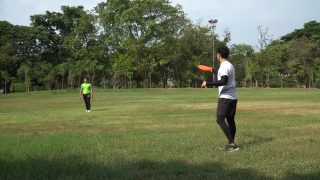 two sport young man playing frisbee in the park . friend exercise together outdoors