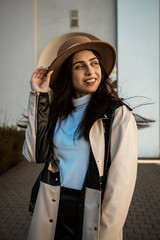 portrait of a young girl in a black and white coat and a beige hat. Walking around the city