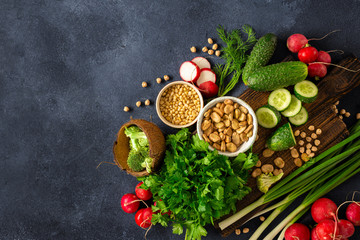 Healthy vegan food veggie cooking concept. Wooden cutting kitchen board with fresh green vegetables, herbs and cereal top view