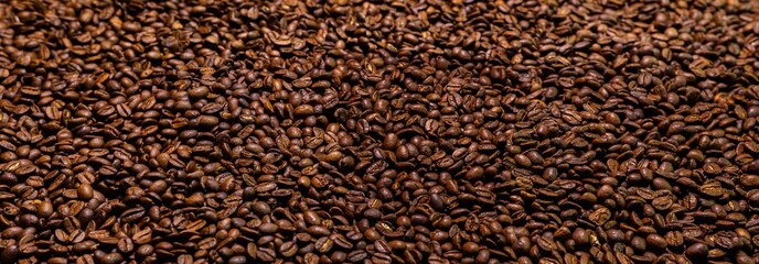 Super large high resolution panorama macro photography of a huge heap of coffee beans. Close up to thousands of roasted coffee beans. Brown roasted beans after roast. Background  wallpaper image