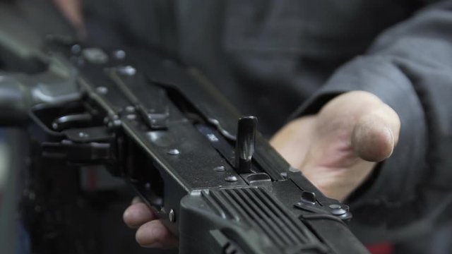 Slow motion charging rifle. Unlocking assault rifle. AK47 loading. Factory worker hand charging machine gun. Factory worker uniforms collects the AK-47